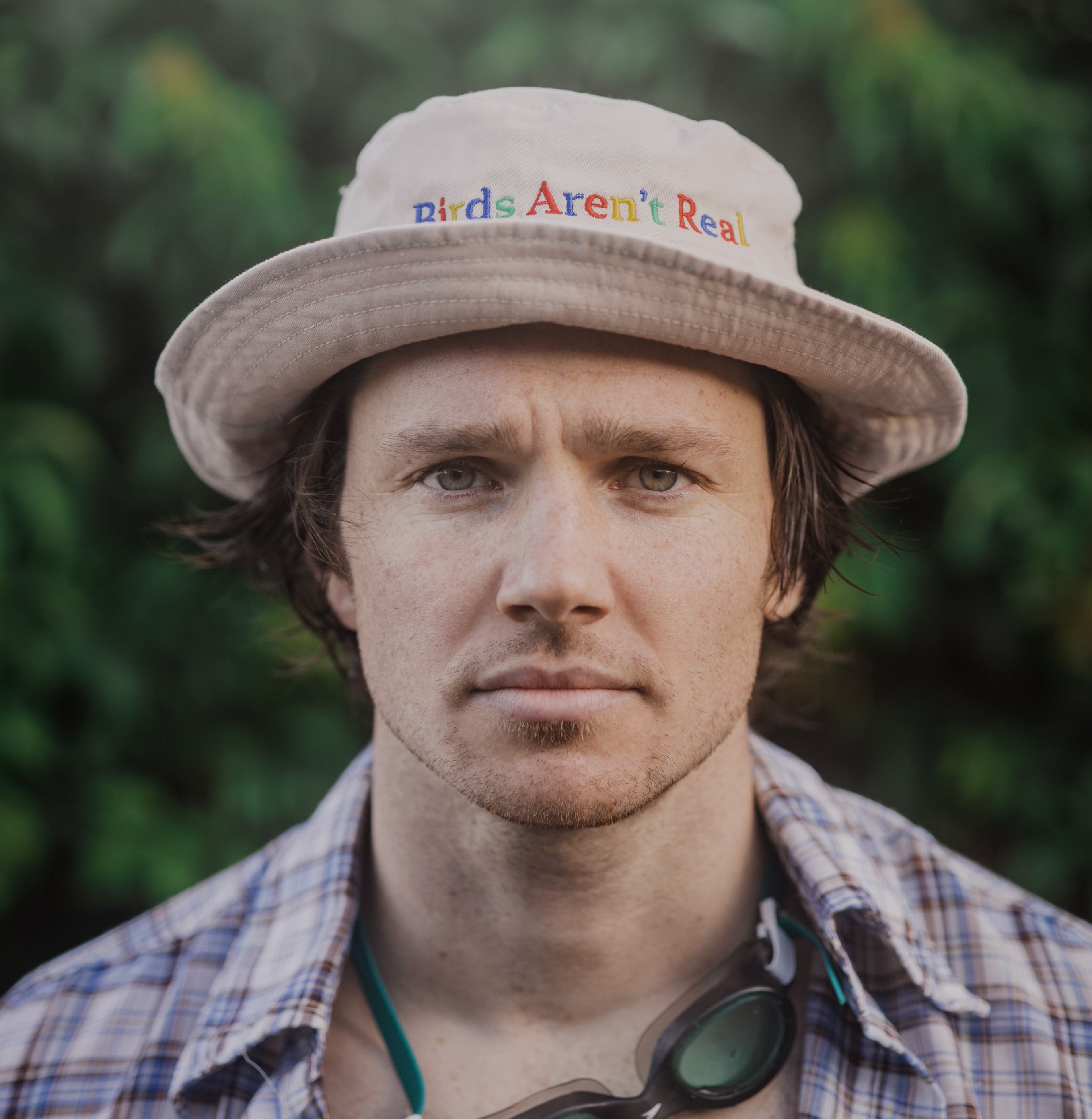 Headshot of man wearing a shirt and a hat looking at the camera