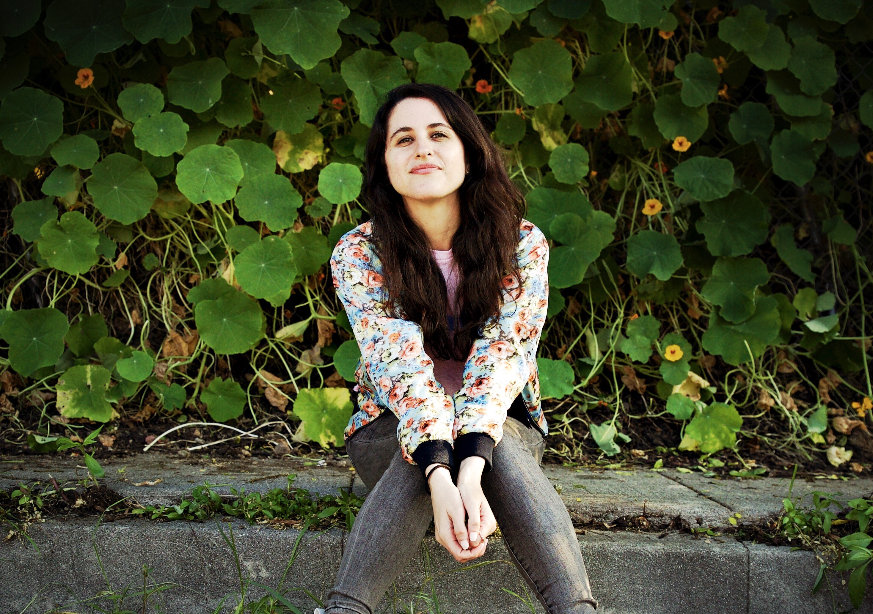 woman with brown hair smiling in front of plants