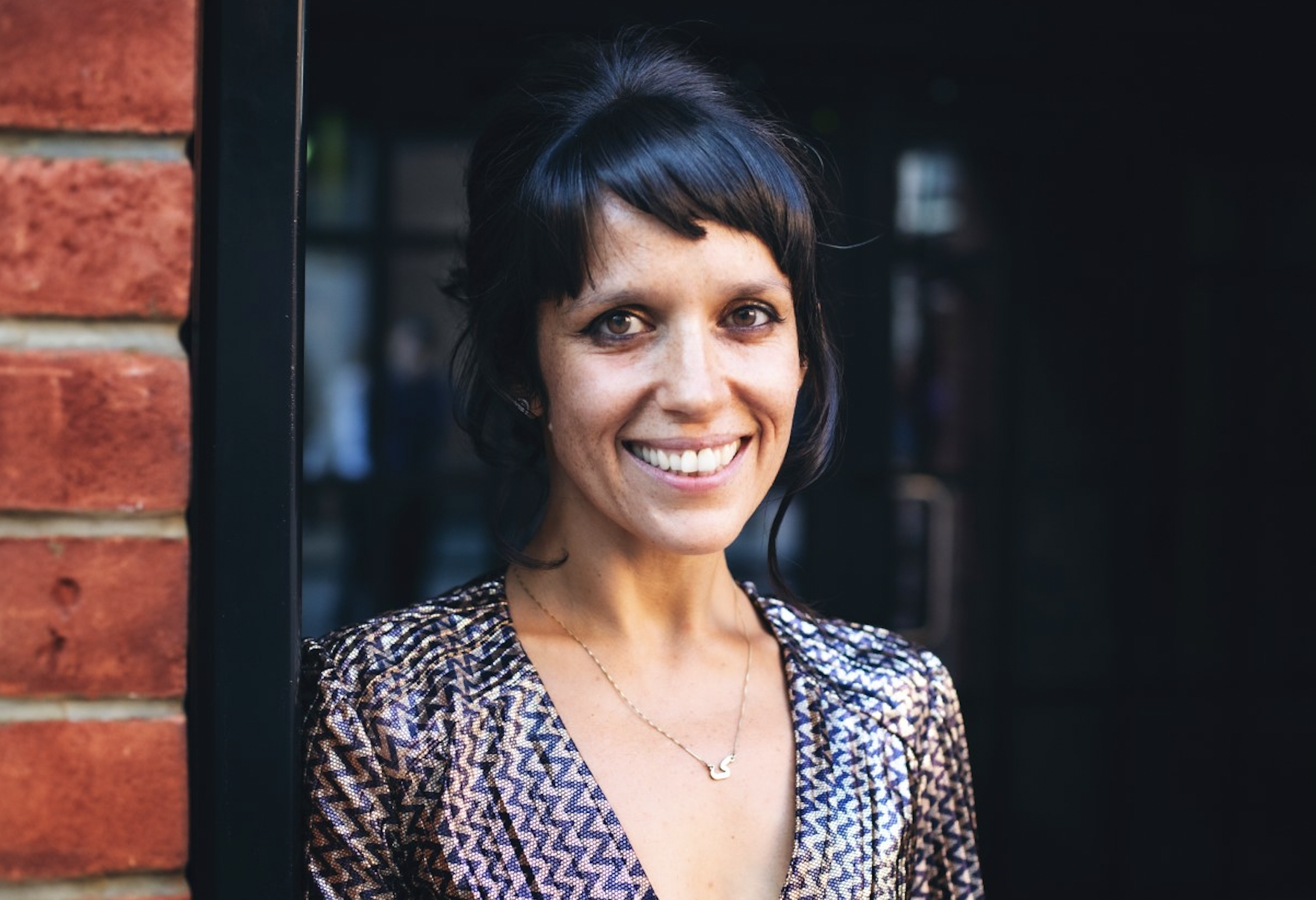 Photo of woman with black hair and bangs, smiling