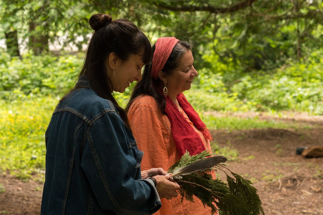 Image of film subject, Kendra and her biological mother, looking down in the forest and smiling