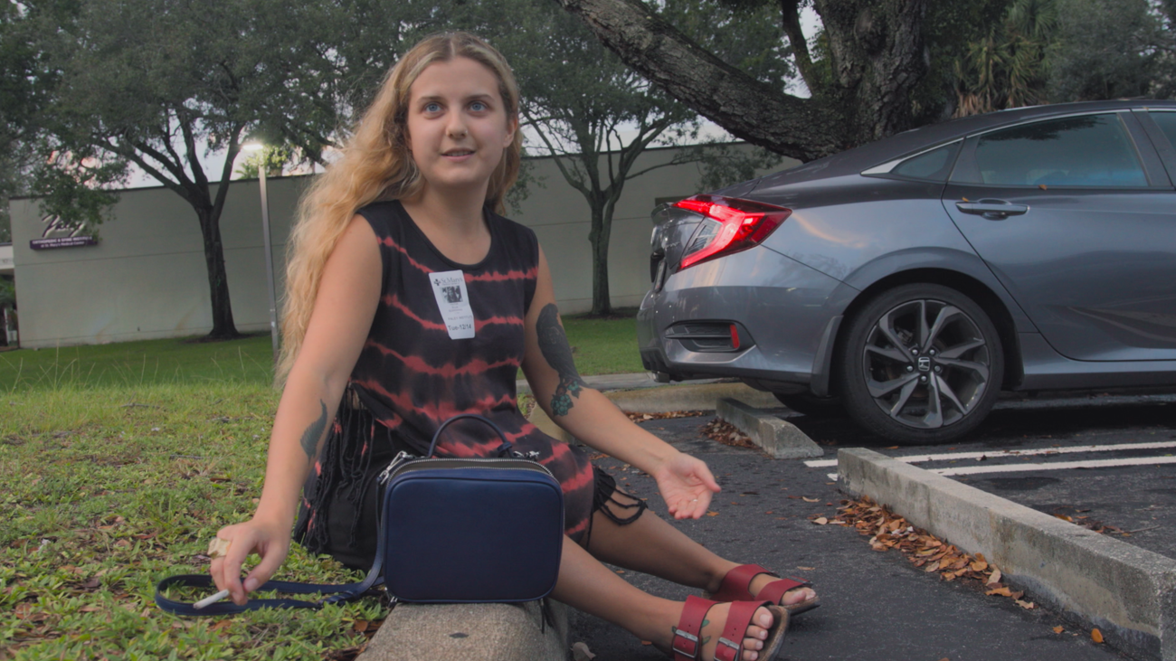 Image of filmmaker Elle Glendining sitting on a curb looking up. 