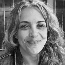 Black and white close up of woman with wavy light hair looking at camera smiling